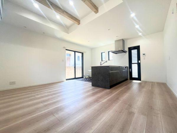 AG-HOUSE　光吉　A棟の居間・リビング|勾配天井に映える木目の梁が空間に温もりを添えるリビング。大きな窓から光がたっぷり差し込み、キッチンとのつながりも感じられる、家族の会話が自然と広がる心地よい空間です！