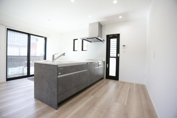 AG-HOUSE　光吉　A棟のキッチン|白とダークカラーのコントラストが美しい対面式キッチン。開放感があり、家族と会話を楽しみながら料理ができる設計。背面ドアや2面採光で換気・採光も良好、快適な家事動線を実現しています♪