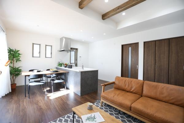 AG-HOUSE　光吉　B棟の居間・リビング|ダークブラウンの床材と化粧梁が織りなす、上質で落ち着いた雰囲気のリビング。勾配天井により開放感も◎
キッチンとの一体感も魅力。ゆったりとした空間で、家族の時間を心地よく過ごせるリビングです♪