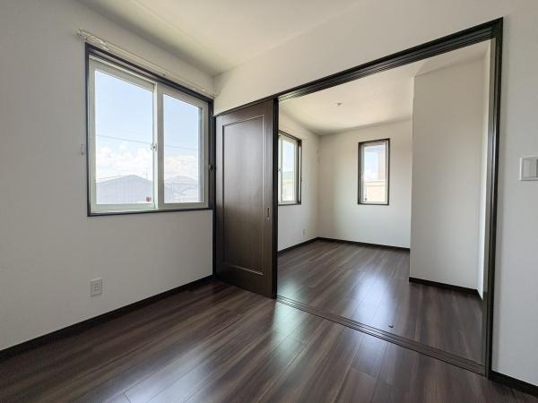 京が丘南4丁目　中古の洋室|明るい日差しが差し込む洋室です。ダークブラウンのフローリングが空間に落ち着いた印象を与えます。仕切り戸を開けることで広がりを感じるレイアウトになっています。窓が複数あり換気もしやすい仕様です。