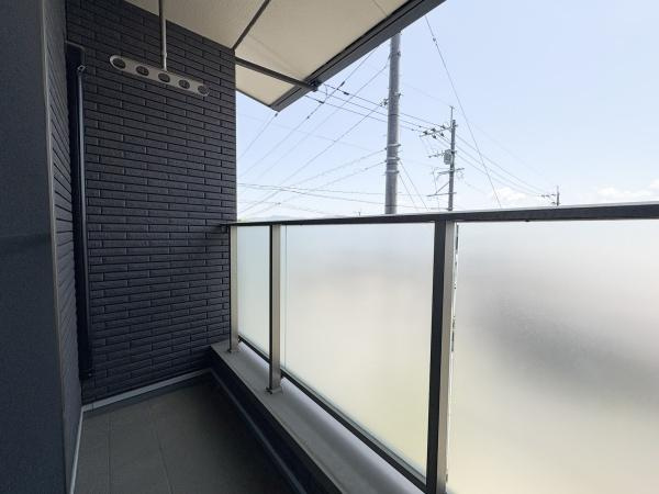 京が丘南4丁目　中古のバルコニー|半透明のガラスパネルが設置されており外からの視線をやわらげる設計です。モノトーン調の壁面が空間を引き締めます。屋根付きなので天候の影響も受けにくい造りになっています。
