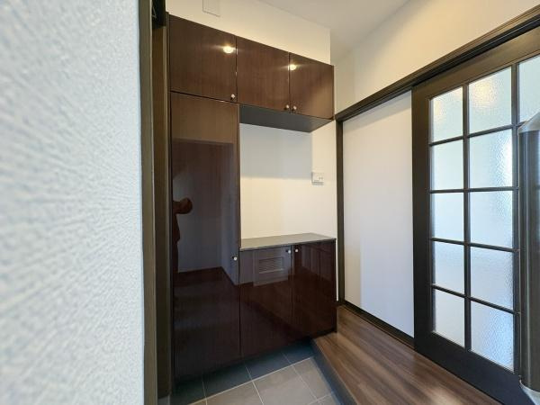 京が丘南4丁目　中古の玄関|玄関には収納力のあるシューズボックスが設置されておりすっきりとした印象です。落ち着いた色味のフローリングと建具が調和し清潔感のある空間です。ドアにはガラスが施されており採光性にも配慮されています。