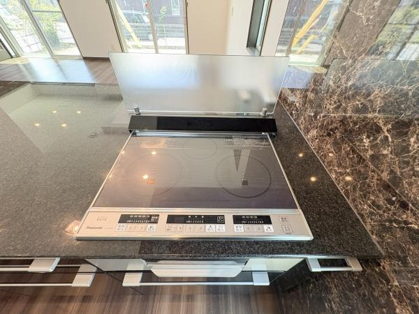京が丘南4丁目　中古のキッチン|光沢感のあるワークトップが特徴的なキッチンです。IHクッキングヒーターが設置されておりお手入れも簡単です。壁面は重厚感のあるデザインで全体的に落ち着いた印象です。収納スペースも豊富に確保されています。