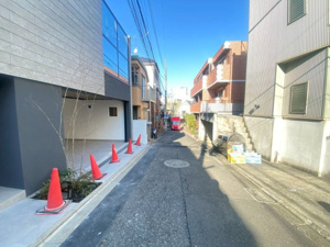 【前面道路含む現地写真】 | 落ち着いた住宅街に佇む、モダンな意匠の住まい。カースペースは建物内に確保されており、雨の日の荷物運びもスムーズです。高低差を活かした設計が、周囲からのプライバシーを守り、落ち着いた暮らしを叶えます。