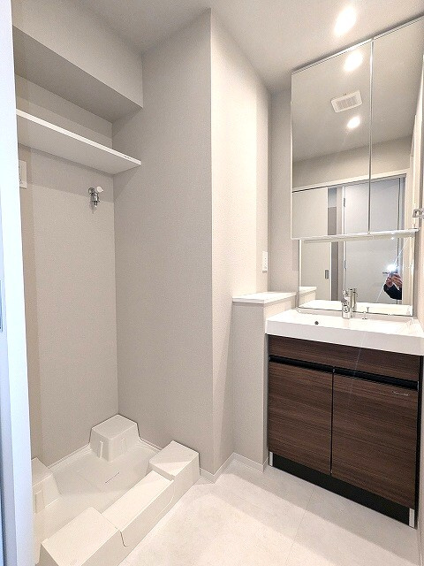Opus Residence上野元浅草の洗面所|二面鏡付・ハンドシャワー付の独立洗面台、室内洗濯機置場、御手入れし易く排水口を手前中央に配置し、足高の防水パンです
