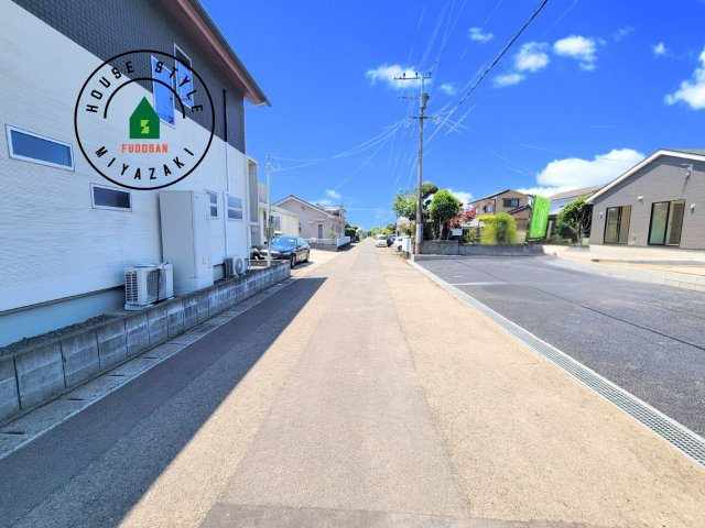 都城市一万城町第2-3棟（2号棟）の前面道路含む現地写真|前面道路は閑静な住宅地をはしる車通りの少ない道路。お車の出し入れが苦手なママや小さなお子様にも安心ですね。しっかり舗装もされているので、ベビーカーや自転車で通っても快適に通行できます。