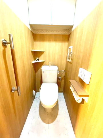 西宮マリナパークシティ海のまち5番館のトイレ|木目調のクロスを前面に貼った落ち着いたトイレ、上部に吊り戸棚収納付き（2017年8月に交換済み）