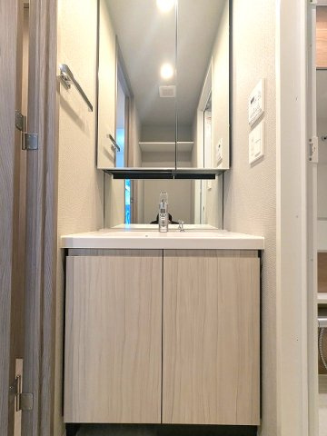 SEASON FLATS上野稲荷町の洗面所|トイレと独立した洗面脱衣室、2面鏡・ハンドシャワー付洗面台、洗面台下にヘルスメーターストックスペースあります、洗面台向かいの洗濯機置場は排水口のお手入れしやすい様に手前中央に配置し、足高の防水パンです