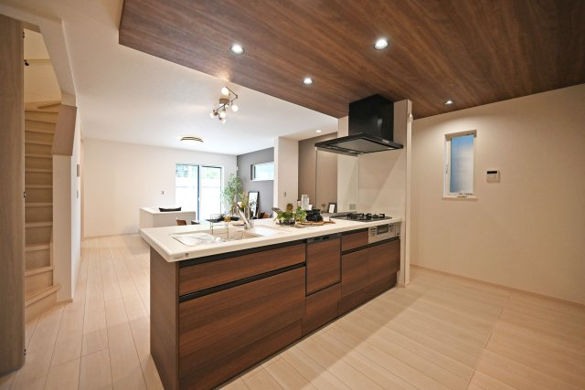 尼崎市東園田町7丁目新築一戸建て│2LDK+2S│並列駐車2台可のその他|1階LDKをキッチンユニット越しに撮影した内観写真です。フルフラットの対面式オープンキッチンを採用しているため視界は広く、ご家族間やご来訪者とのコミュニケーションも一体的に取り易くなっております。