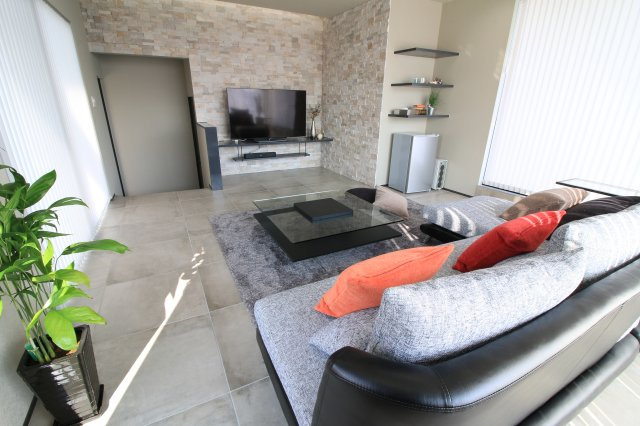 太田市粕川町中古戸建の居間・リビング|リビングの壁には作り付けの家具に本物の石を使ったタイルが施してあり間接照明もあります。