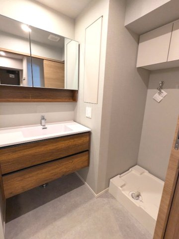 ミリアレジデンス蔵前の洗面所|トイレと独立した2面鏡付洗面台、洗面台下にヘルスメーターストックあります、洗濯機置場はお手入れし易い様に排水口を手前中央に配置し、足高の防水パンです