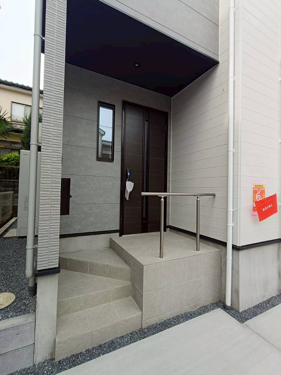 三郷市　後谷　新築戸建　全1棟の外観|手すり付きで安心感のある玄関アプローチ。階段の上り下りをしっかりサポートしてくれるため、小さなお子さまからご年配の方まで使いやすい設計です。玄関まわりはゆとりのあるつくりで、毎日の出入りもスムーズ。