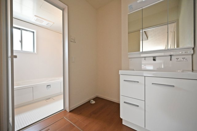 テラシエ水明台2丁目新築一戸建て│5LDK+駐車並列2台可の独立洗面台|1階洗面室に入ってすぐの内観写真です。900mm幅のシャンプードレッサーを導入しており、広々と使用できます。十分な明るさのある2照明を採用し、朝支度もスムーズに進みます。