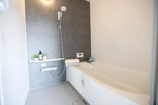 センチュリータウン関園ⅡNの浴室|シンプルで清潔感のあるバスルームです。ダークトーンのアクセントパネルが落ち着いた印象を与えます。シャワーヘッドや操作パネルが機能的に配置されています。浴槽は広々とした造りで快適です。