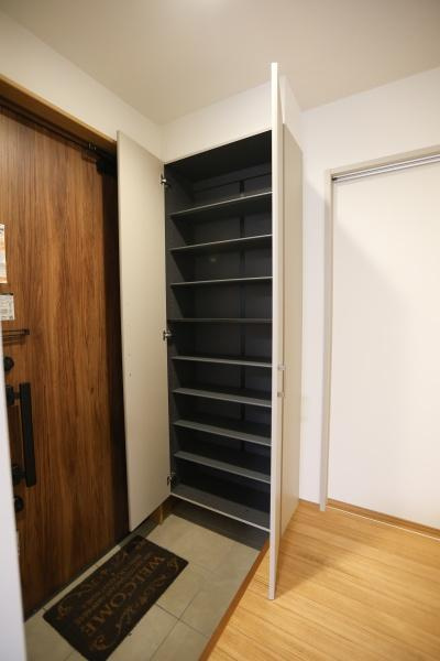 センチュリータウン関園ⅡNの玄関|玄関には扉付きの収納スペースが備わっています。シンプルなデザインの玄関ドアが印象的です。収納棚は高さが調整でき使いやすさに配慮されています。玄関周辺がすっきりと整います。
