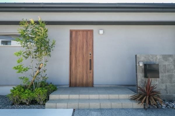 センチュリータウン関園ⅡNの玄関|シンプルで落ち着いたデザインの玄関は清潔感があります。タイル敷きのアプローチが印象的です。木目調のドアが外観に温かみを与えています。植栽がさりげなく彩りを添えています。