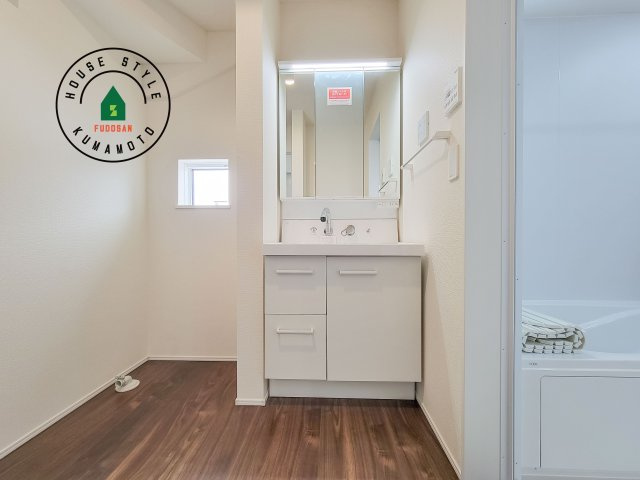 合志市須屋群窪第1-2棟（2号棟）の独立洗面台|毎日使うものだから清潔な空間を保ちたい水回り。洗面にはそんな願いを解消させてくれる収納アイデアが満載です。三面鏡の裏側にはキャビネットが現れ小物から背の高い物まで収納できます。