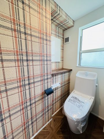 Beach Style House in茅ヶ崎のトイレ|チェック柄クロスと無垢フロアの組み合わせで、遊び心のある空間に。
