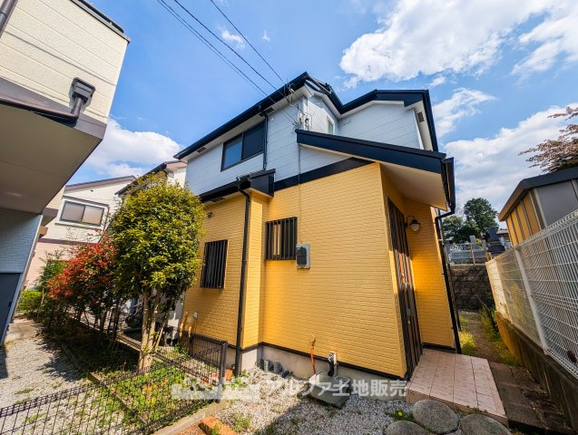 日野市南平4丁目　中古戸建の外観|明るいイエローの外観が印象的な一戸建て。植栽スペース付きで、ガーデニングも楽しめる住まいです。