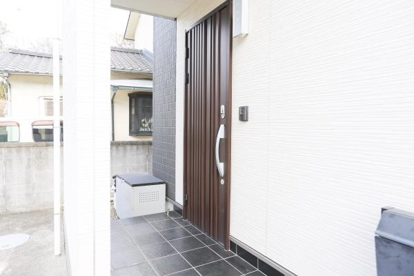 別府南立石　中古の玄関|落ち着いた色合いの玄関ドアが印象的です。タイル張りのアプローチで清潔感があります。収納ボックスも設置されていて便利に使えます。門まわりもすっきりとしたデザインです。