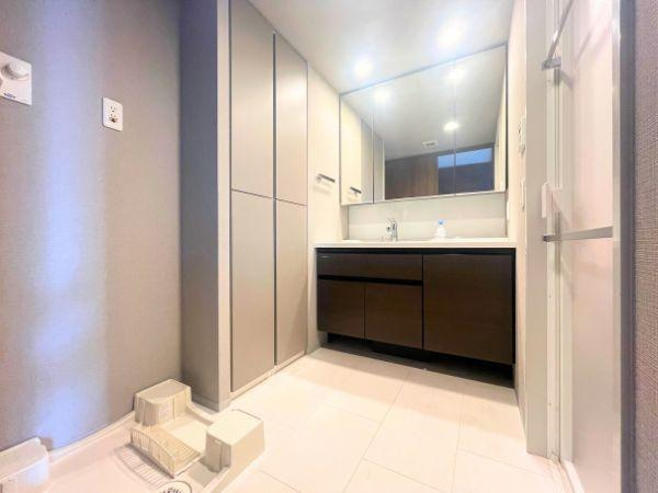 デュオヒルズ大分中島の独立洗面台|大きな鏡とたっぷりの収納を備えた洗面化粧台で、朝の支度も快適に。洗濯機置き場にもゆとりがあり、使い勝手の良さが魅力です！落ち着いた色合いの洗面台が、清潔感と上質な雰囲気を演出してくれる空間です♪