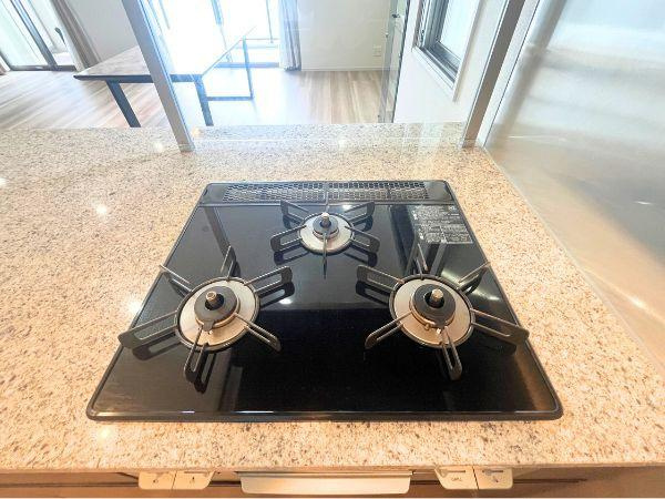 デュオヒルズ大分中島のキッチン|光沢のあるガラストップが美しい三口コンロは、デザイン性とお手入れのしやすさを両立。広々とした配置で、複数の料理も同時に調理でき、毎日の家事がスムーズに。スタイリッシュで機能的なキッチンを演出します！