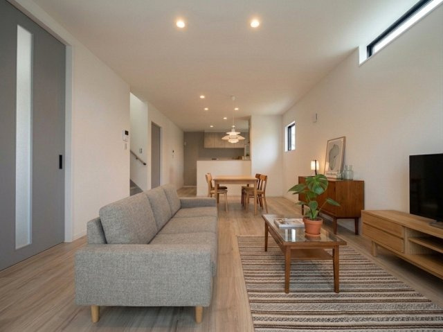 藤田一丁目の居間・リビング|木の温もりと、グレーの建具が調和したモダンなリビング。高窓から光が差し込む開放的な空間です。　※家具・インテリアはAIによるイメージです。家具等は販売価格に含まれません。