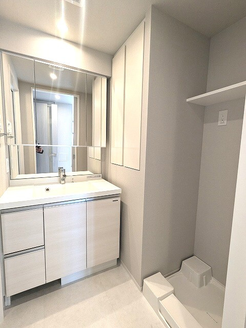Opus Residence上野元浅草の洗面所|三面鏡付・ハンドシャワー付の独立洗面台、洗面台下にヘルスメーターストック付き、室内洗濯機置場、御手入れし易く排水口を手前中央に配置し、足高の防水パンです