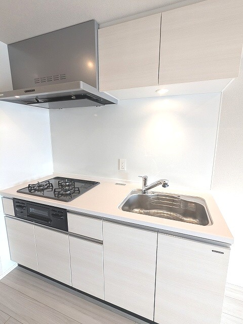 Opus Residence上野元浅草のキッチン|グリル付ガス3口システムキッチン、瀟洒でお手入れ楽なガラストップコンロ、広々のシンク、ハンドシャワー、豊富な収納
