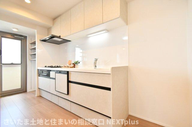 セレナハイムパークステージ桶川のキッチン|白基調の吊戸棚付きシステムキッチンです。上にも下にもたくさん収納出来ますので、別途で食器棚がなくてもたくさん収納する事ができます！ライトもありますので、お料理中の手元もしっかり照らしてくれます。