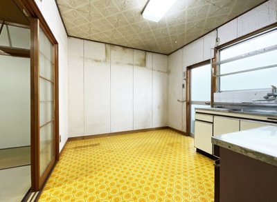 【居間・リビング】 | 上京区御前通下立売上る三丁目東入三助町　中古戸建 | キッチンスペースには明るい窓があり、勝手口も設置されております。こちらは食卓スペースとし、隣の和室を居間（リビング）として利用出来ますね。