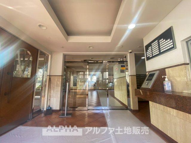 モナーク聖蹟桜ヶ丘のエントランス|開放感のあるエントランスホール。ガラス扉の向こうには光が差し込み、落ち着いた雰囲気の中で住まう人を迎え入れます。オートロック付きでセキュリティ面も充実し、住む人に安心と快適な暮らしを提供します。