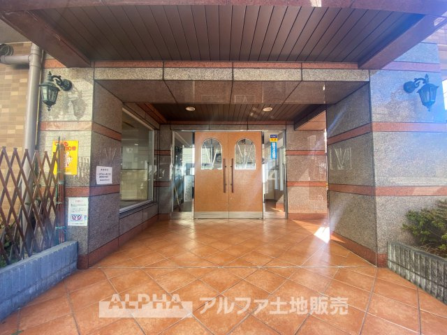 モナーク聖蹟桜ヶ丘のエントランス|温かみのあるタイル張りのエントランスが、住まいへと誘います。落ち着いたデザインと広々とした空間が、毎日の暮らしにゆとりをもたらします。