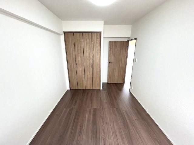 忠道マンションA棟の洋室|落ち着いた木目調のフローリングと白壁が清潔感あふれる洋室です。クローゼットが完備されており、居室スペースを広くお使いいただけます。
