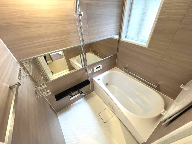 忠道マンションA棟の浴室|温かみのある木目調の壁が、リラックスできる空間を演出するバスルーム。半身浴も楽しめるゆとりのある浴槽で、一日の疲れをゆっくりと癒せます。大きな鏡が空間に広がりを感じさせます。