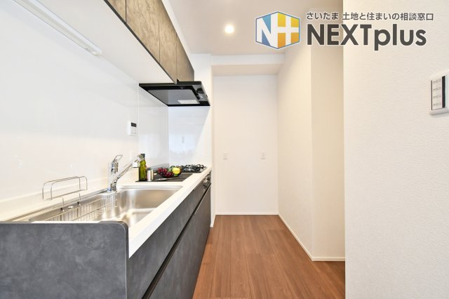 ライオンズシティ春日部のキッチン|黒基調の吊戸棚付きシステムキッチンです。上にも下にもたくさん収納出来ますので、別途で食器棚がなくてもたくさん収納する事ができます！ライトもありますので、お料理中の手元もしっかり照らしてくれます。