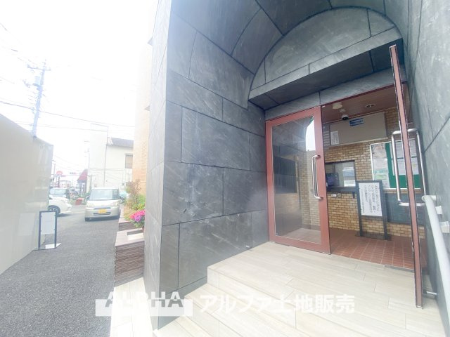 ライオンズマンション高幡不動の外観|陽射しに映えるエントランスのプレートが、品格ある佇まいを演出。周囲の緑と調和し、落ち着いた住環境が広がります。快適な暮らしを叶える、魅力的なマンションです。