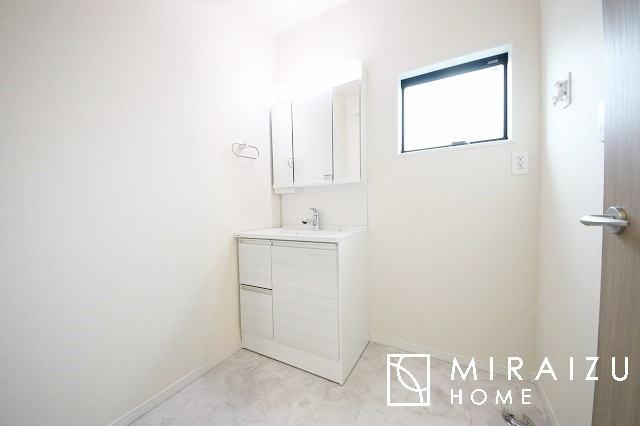 【洗面所】 | 洗濯機置き場と脱衣スペースもしっかりと確保されている洗面室、洗面コーナーは、窓から陽も差し明るく開放的な造りです。家事導線も良いので洗濯物やお湯はりもストレスフリーに毎日家事を楽しめそうです。
