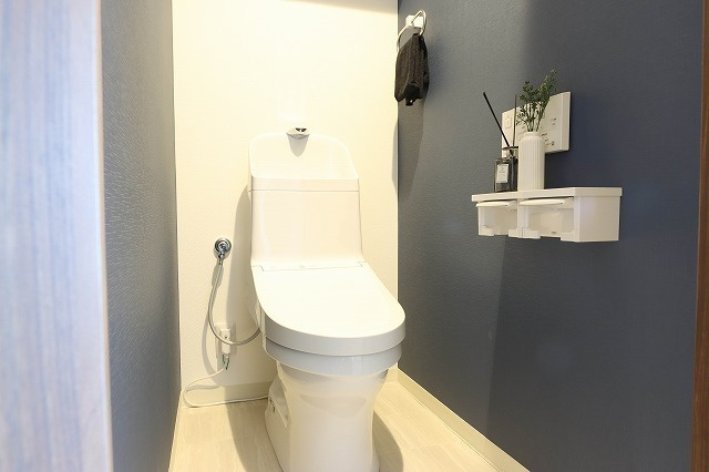 ディアステージ奥田公園のトイレ|ネイビーグレーのアクセント壁が映える温水洗浄便座付トイレ。落ち着きある色調とすっきりした設えで、毎日のリフレッシュタイムを上質に演出します。