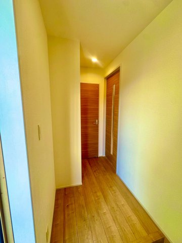 ブルーミングガーデン西原町小那覇・１号棟の内装|玄関からリビングへ続く廊下／木目調の扉は開閉がスムーズで指を挟みづらいソフトクローズ機械を採用◎