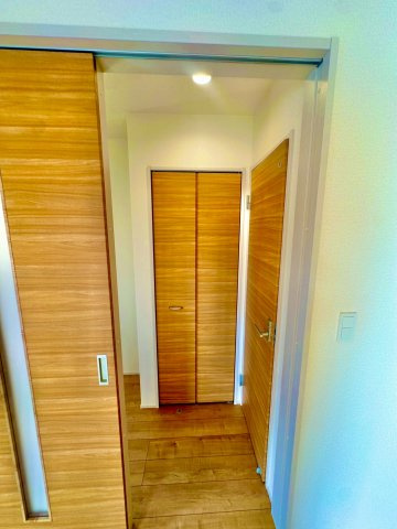 ブルーミングガーデン西原町小那覇・１号棟の内装|リビング側から見た廊下／木目調の扉は開閉がスムーズで指を挟みづらいソフトクローズ機械を採用◎