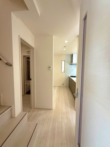 ブルーミングガーデン西原町小那覇・２号棟の居間・リビング|玄関からリビング＆階段へつづく廊下／入口側には洗面室があり帰宅後する手洗いも◎