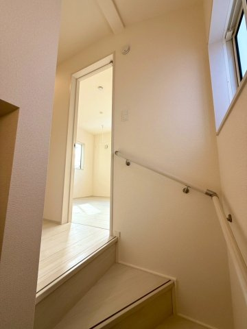 ブルーミングガーデン西原町小那覇・２号棟の内装|手すり付き階段／２階廊下には採光が取れる窓付き