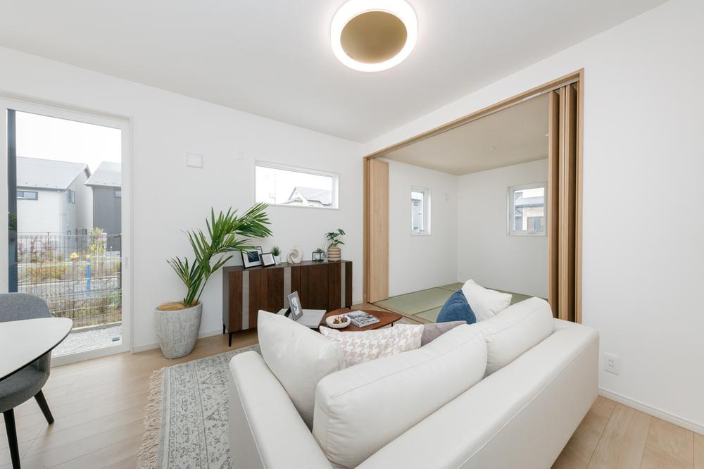 【兼六パークタウン】花小金井33期　全42棟残１棟！の居間・リビング|LDK、和室が隣接し、扉を開放すると19帖超の広々空間に！フロアやキッチンのポップアップ天井などに明るい木目をふんだんにあしらい、ナチュラルな印象のLDKと、違和感なく調和します。