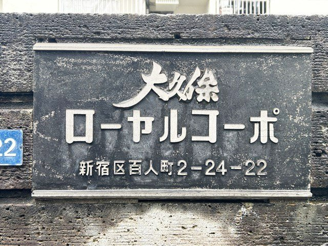 【現況写真】 | 大久保ローヤルコーポ | エントランスに掲げられた、マンション名を示す館銘板。さほど激しく主張はしませんが、しっかりと掲示されています。～即日のご見学可能～　お問合せはお気軽にどうぞ。
