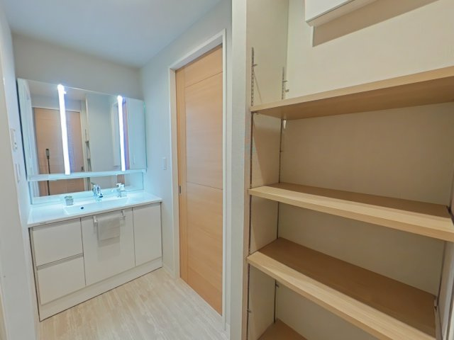 サーパス医大南の洗面所|脱衣スペースは白と木目を基調とした明るく、清潔感のある空間です。