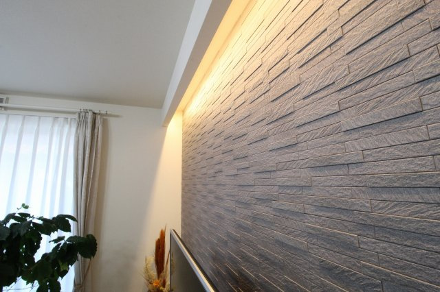 小山市羽川の居間・リビング|調湿効果に優れたエコカラットが一面に。LEDの間接照明で、くつろぎタイムがより心地よいひとときに◎