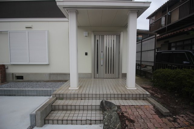 小山市城北4丁目の玄関|白を基調とした外観に映える玄関ポーチ。屋根付きで雨の日も安心、重厚感あるドアが来客を迎えます。