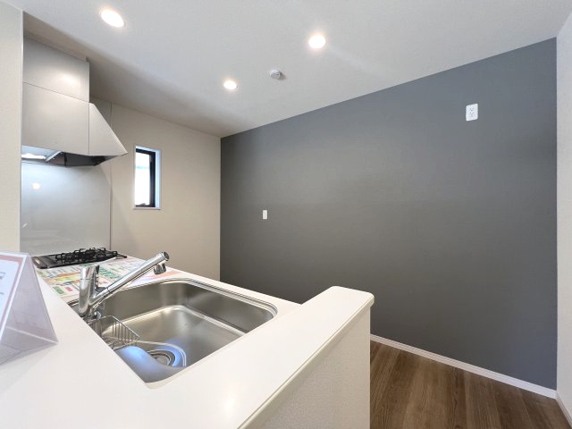 碧南市住吉町2期　新築分譲住宅　１号棟のキッチン|アクセントカラーでまとめられたキッチンの壁紙は流行色でありながら上質な印象です。