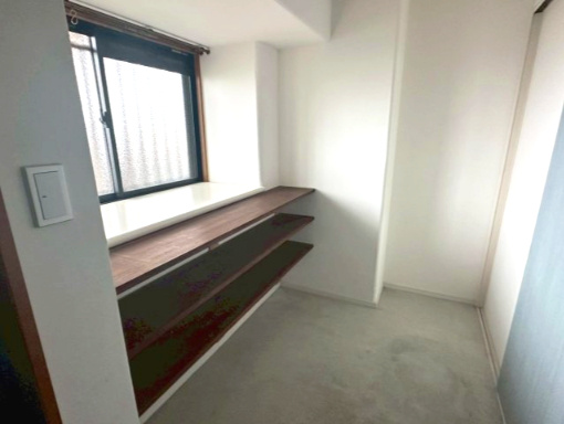 サーパス久保田の玄関|リノベーションにより玄関土間を広げ、広々とした空間で靴や趣味の道具を収納できます。窓辺の空間を有効活用した、造り付けの木製棚が魅力です。